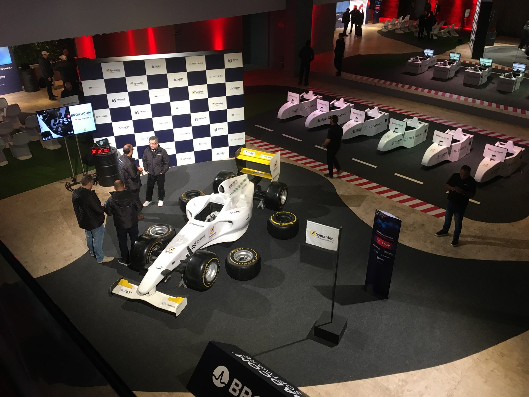 Vista aérea do Pit Stop Experience em evento corporativo Broadcom — réplica de F1, pista demarcada e simuladores ao redor